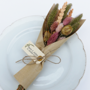 Bouquet de fleurs séchées dans les tons roses poudrés et naturels emballé dans un joli papier kraft avec une étiquette personnalisée